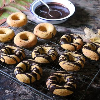 Donuts being covered in the chocolate drizzle.