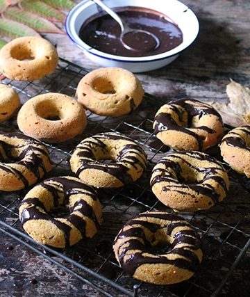 Donuts being covered in the chocolate drizzle.
