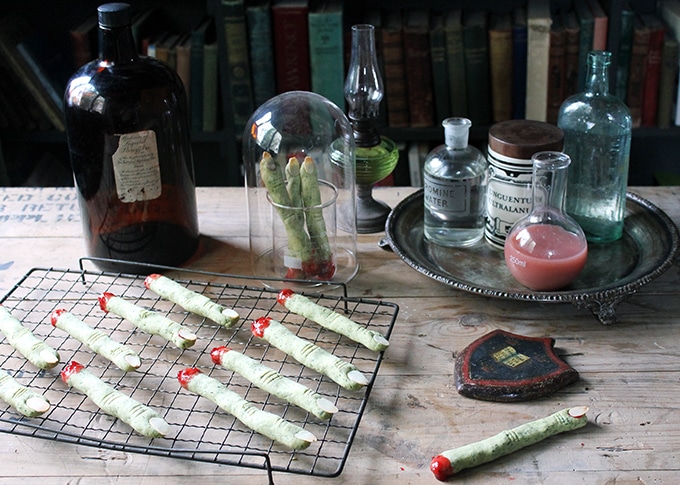 A spooky table with a rack of witch fingers cookies, science beakers and jars of potions.