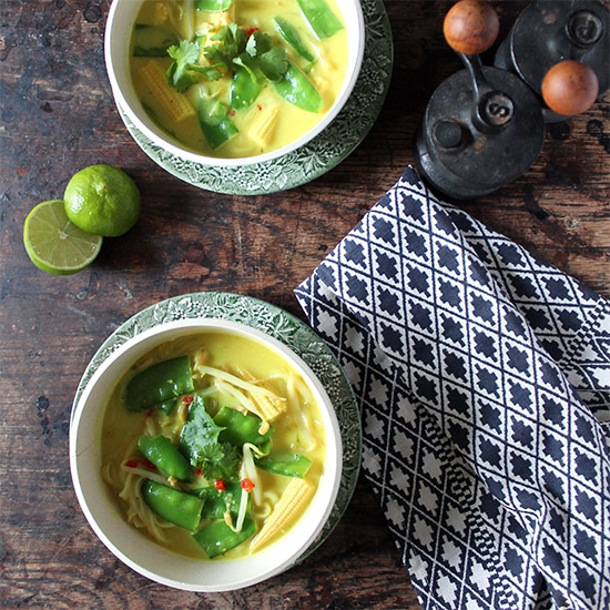 Easy Vegan Laksa in bowls on a wooden table with sliced limes