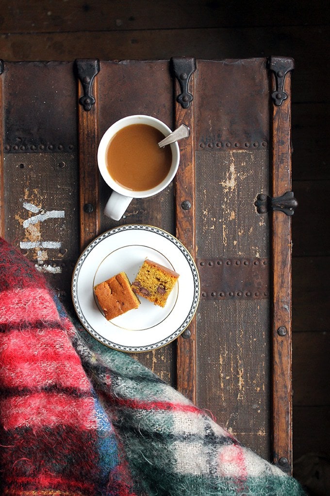 A plate of cake and a mug of tea on a wooden table.
