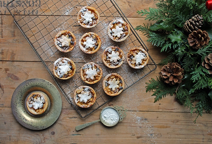 Sweet Apple and Cider Mince Pies with Cheddar Pastry on a cooling rack next to pine branches and pine cones.