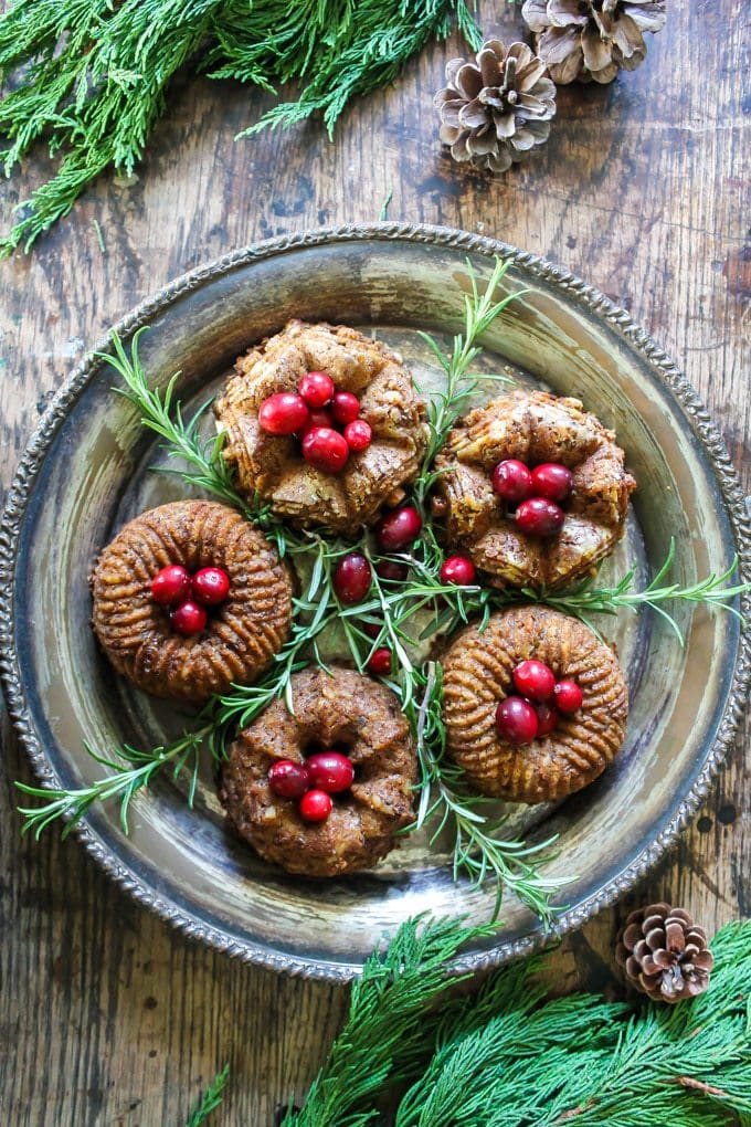 Mini bundt chestnut roasts on a vintage silver platter with cranberries piled on top with rosemary sprigs.