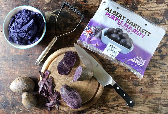 Purple potatoes being peeled and cut.