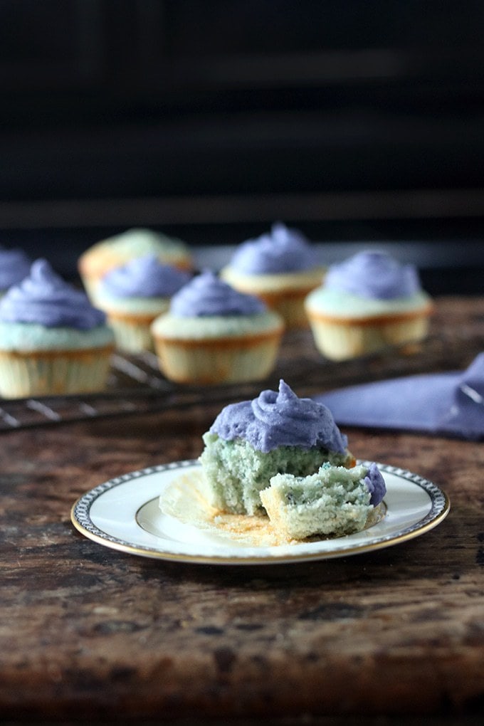 A close up of a cupcake on a plate, with a bite out.