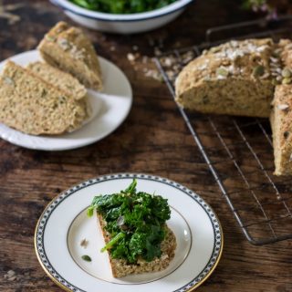 A table with a slice of bread on a plate, topped with steamed kale.
