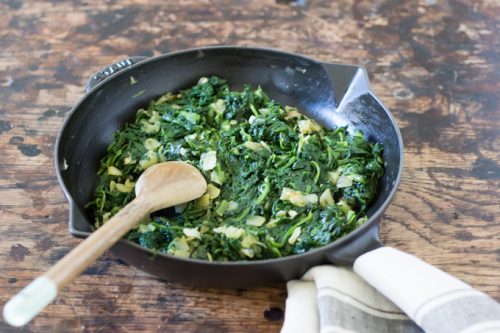 Skillet of spinach and onions cooking.