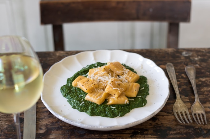 Homemade sweet potato gnocchi on a plate with spinach sauce.