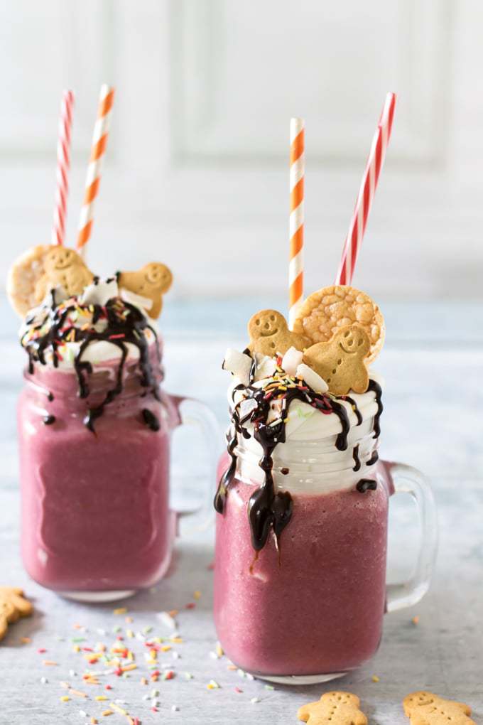 Mugs of smoothie topped with cream, cookies and straws.