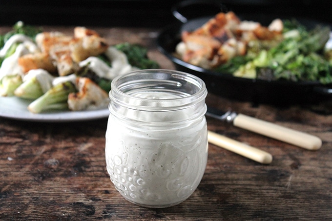 A jar of homemade creamy cashew-based Caesar dressing on a table.