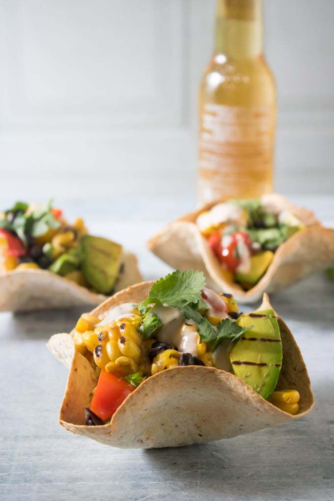 Close up of Mexican Chipotle Grilled Salad in Tortilla Bowls with a Mexican beer in the background.
