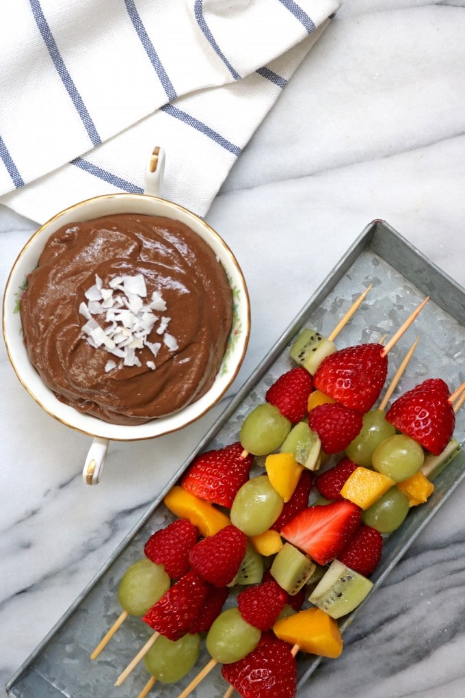 Dish of chocolate dip and fruit skewers.