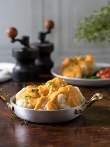 A dish of cauliflower cheese on a wooden table.