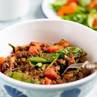 A bowl of lentil stew with spinach.