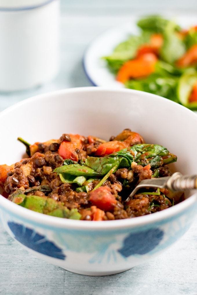 A bowl of lentil stew with spinach.