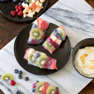 A plate with fruit wrapped in rice paper on a marble board.