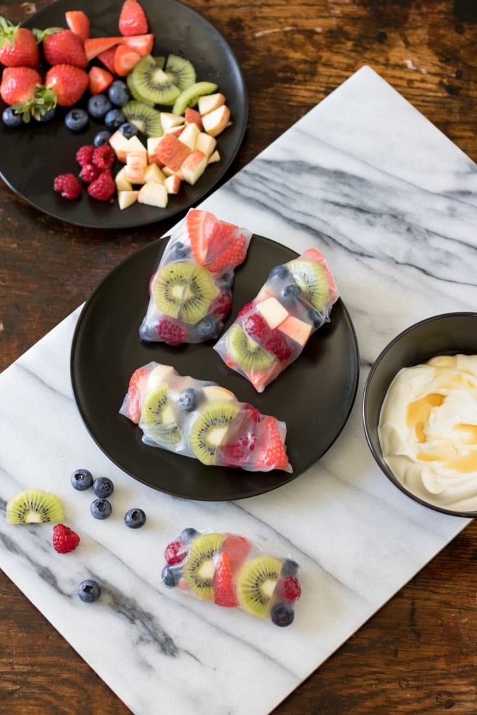 Fruit Summer Rolls with Vanilla Yogurt Dip on a plate with extra fruit. 