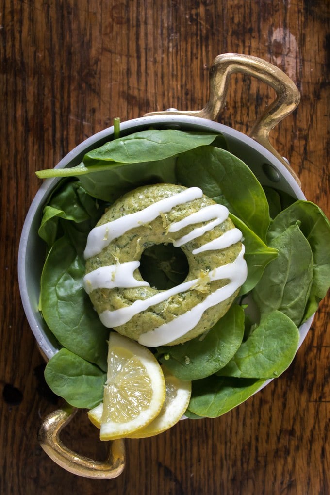 Donut on a plate of spinach leaves.