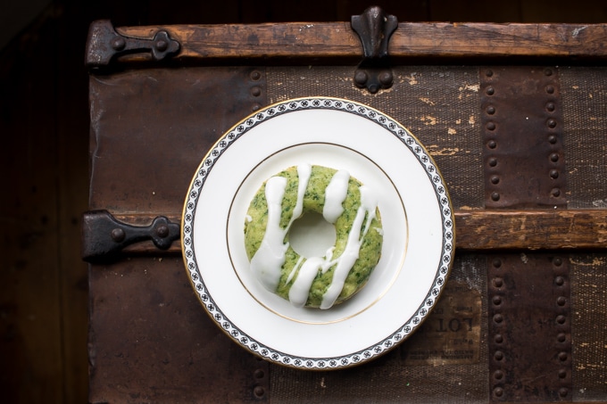 Spinach donut with glaze on a plate on a vintage trunk.