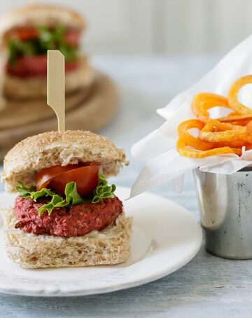 Mini beet burger on a plate next to fries.