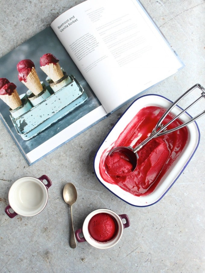 A dish of beet ice cream next to a book.