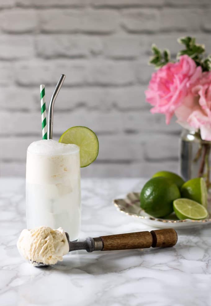 Ice cream float with a scoop of ice cream in front and a vase of flowers.