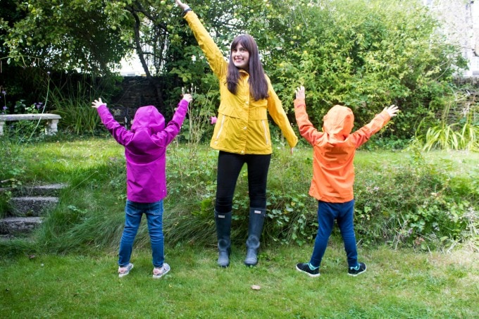 Mother and two kids in bright coats in a field.