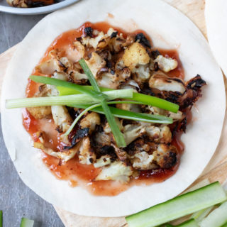 Vegan Chinese Crispy Duck made with cauliflower, served on homemade Chinese pancakes with plum sauce and strips of scallions.