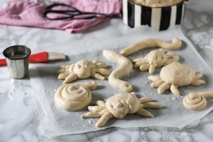 Dough shaped like spiders and snakes on a table.