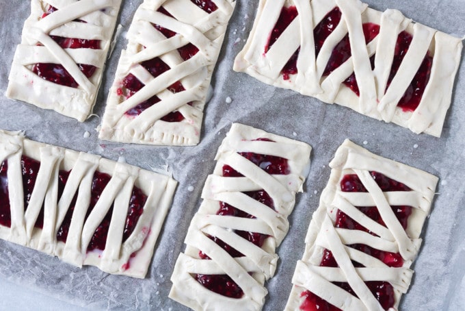 Rectangles of puff pastry spread with raspberry puree and strips of puff pastry angled over the top to look like mummies.