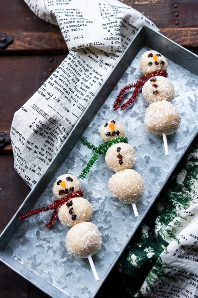 Bliss balls shaped like snowmen on a metal tray.