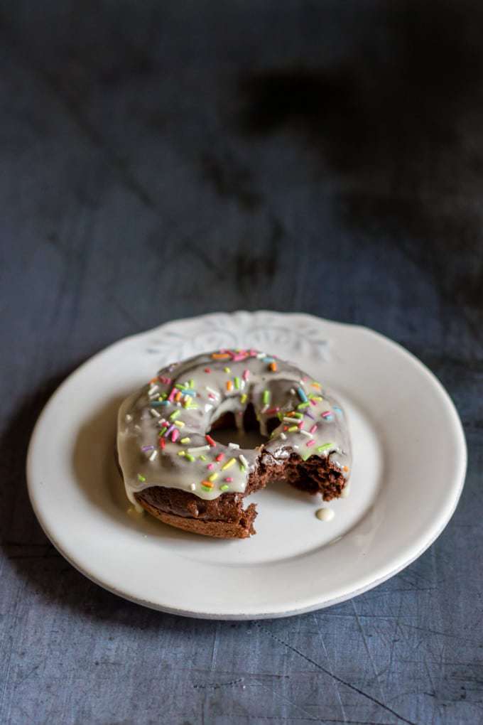 Donut with a bite out on a plate.