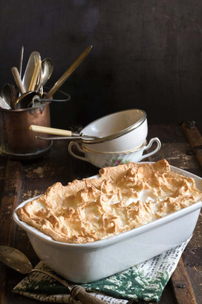 A dish of queen of puddings in front of vintage serving bowls.