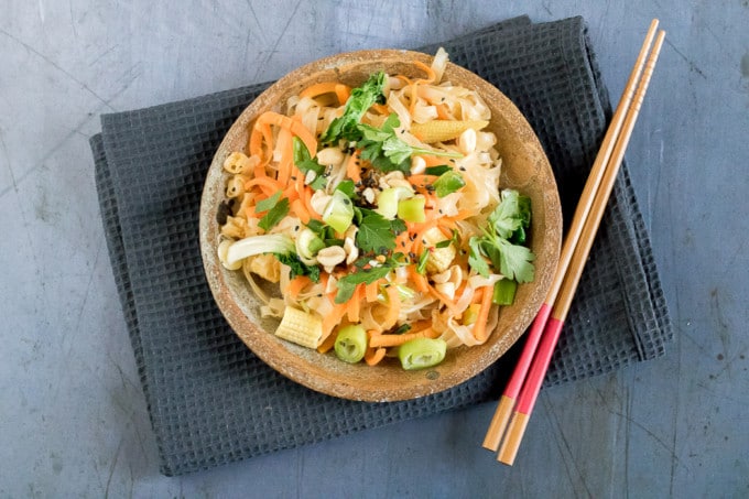 Overhead shot of a bowl of 15 minutes vegan pad Thai. Rice noodles and carrot ribbons are mixed with fragrant spices and fresh vegetables. 