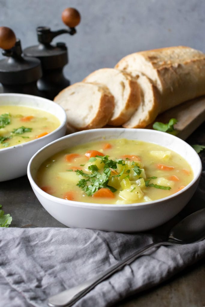 A bowl of vegetarian and vegan Irish stew next to slices of bread