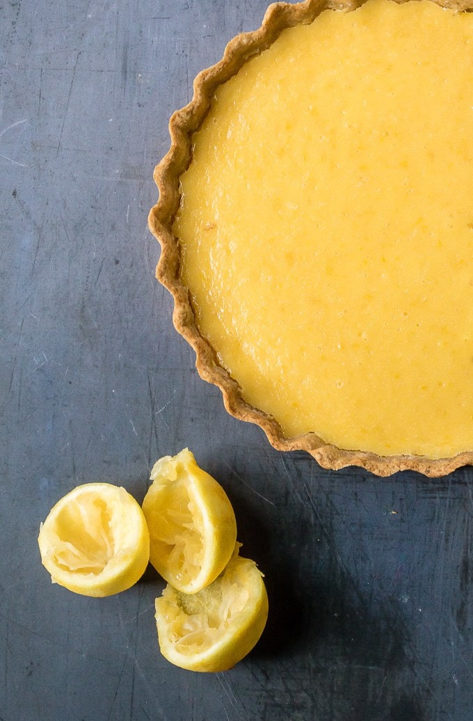 Overhead shot of lemon tart with chamomile crust next to lemons.