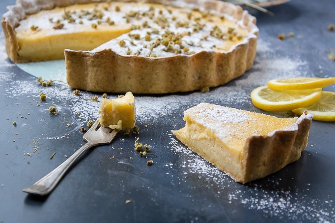 A fork full and slice of lemon tart with chamomile crust and chamomile infused icing sugar.