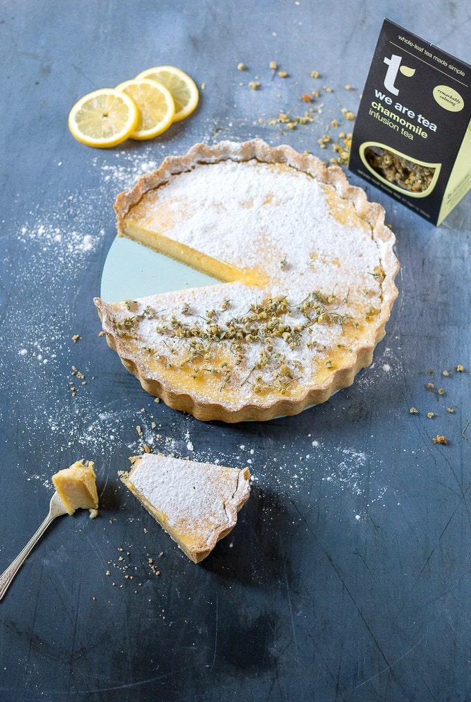 A slice from a lemon tart with chamomile crust next to a box of tea.