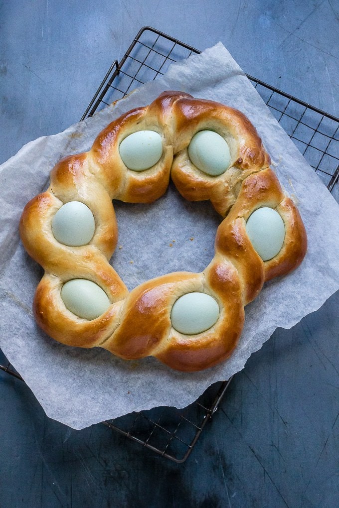 Braided Easter Bread cooling on a rack, with pale blue eggs nestled in the ropes of the braids.