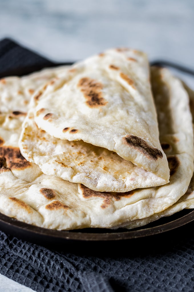 A folded fluffy yeast-free naan bread on a stack of other naan breads.