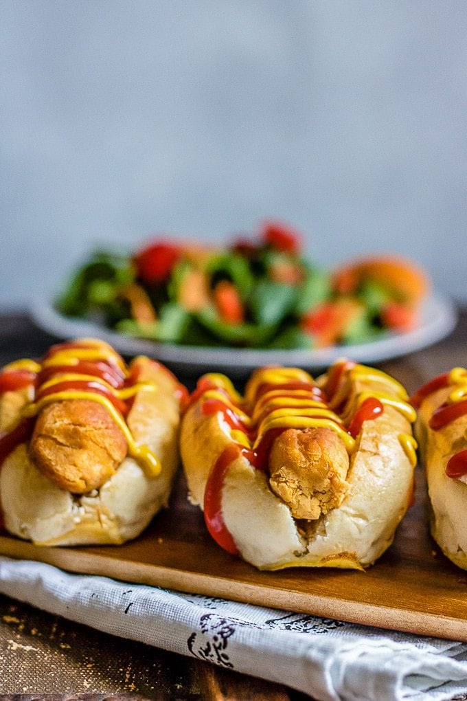 Veggie hot dogs close up - lentil and carrot hot dogs in buns in front of a bowl of salad