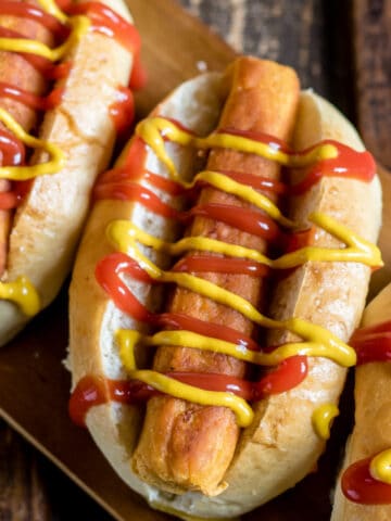 Looking down at lentil hot dogs with mustard and ketchup.