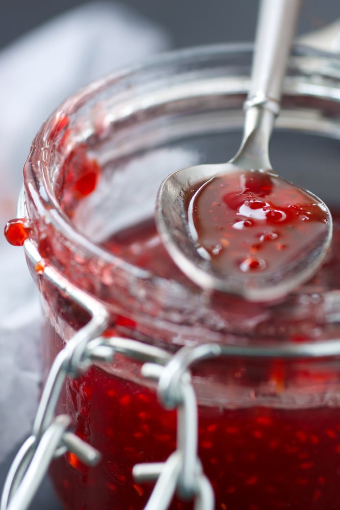 Spoon in a jar of raspberry compote.