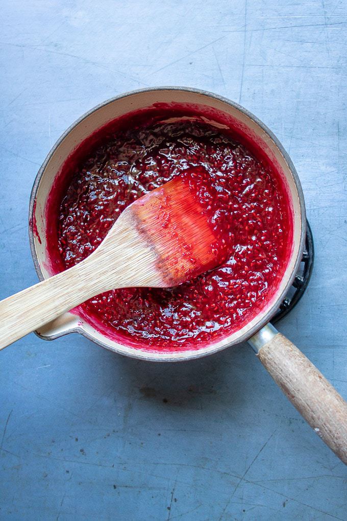 Pot of raspberries heated with sugar and lemon juice.