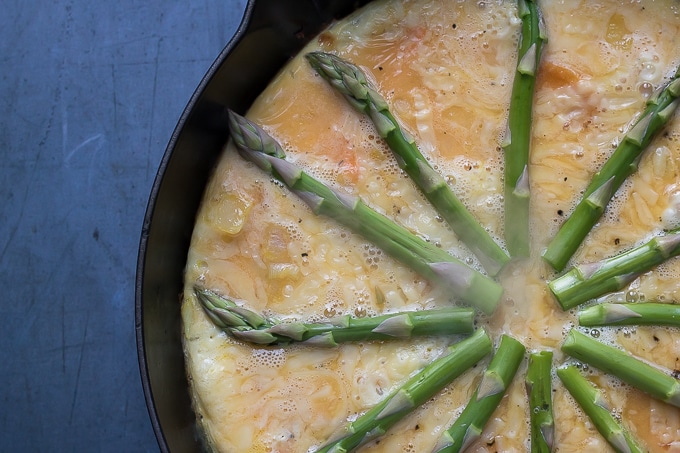 Pan of eggs and asparagus ready to be cooked.
