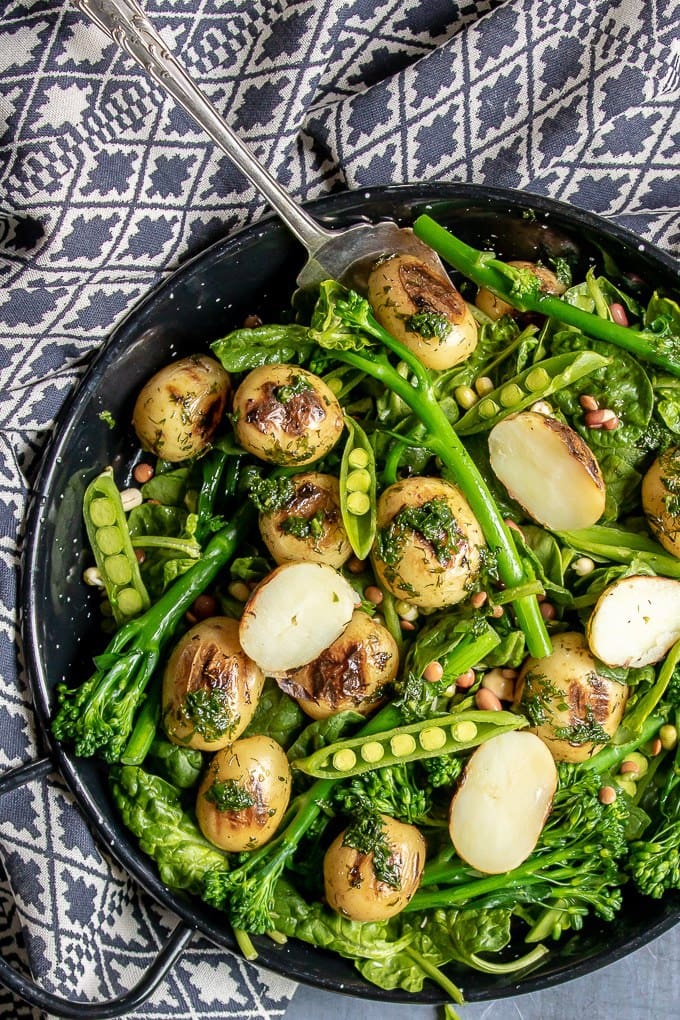 Close up of a blue patterned tea towel with a bowl of broccoli salad.