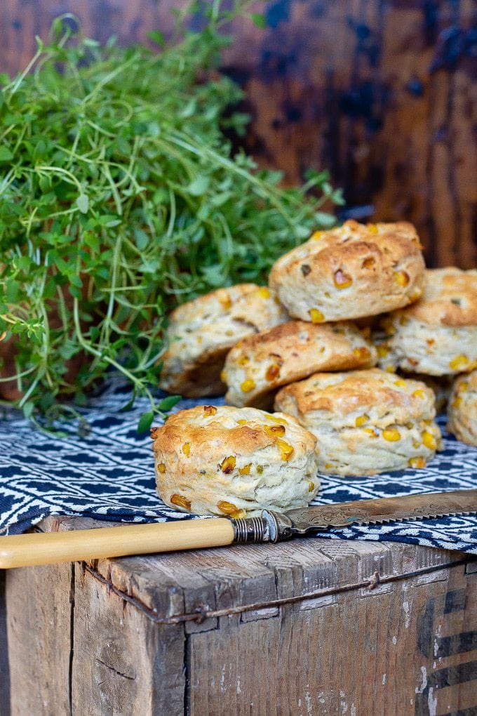 Close up of sweetcorn and jalapeno goats cheese scones on a vintage crate with knife and pot of thyme
