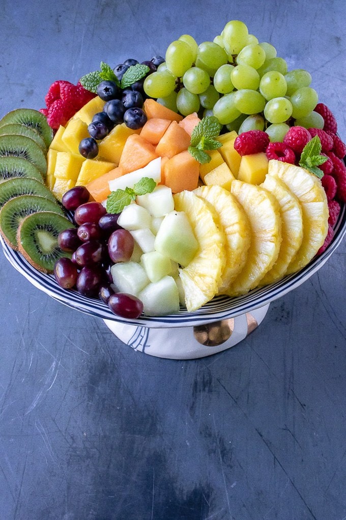 Fruit platter laid out on a cake stand with piles of fresh fruit