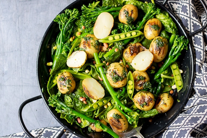 A bowl of pea potato broccoli salad with herb dressing.