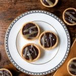 Close up of three mini chocolate tarts with salted caramel drizzle on a white plate. Get the recipe.